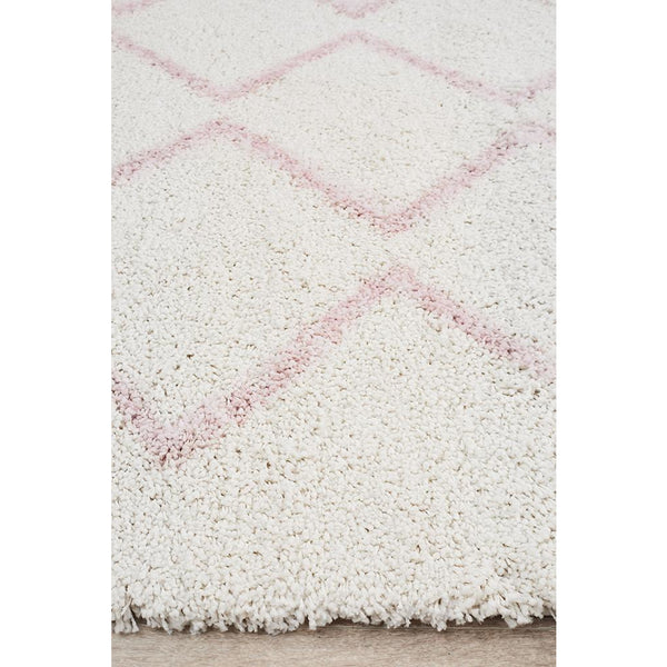 White shaggy rug with soft pink Moroccan diamond pattern and plush texture.