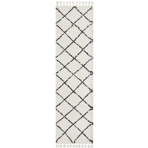 White shaggy runner rug with black Moroccan diamond pattern and fringed edges.