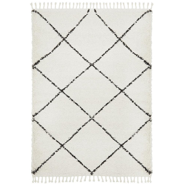 White shaggy rug with black diamond Moroccan-inspired tribal pattern and fringe edges.