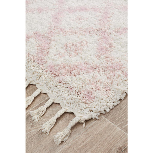 Pink Moroccan-inspired shaggy runner rug with cream tassel fringe on light wood floor.