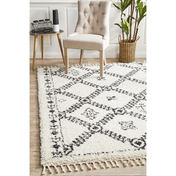 White shaggy rug with black Moroccan-inspired geometric and tribal patterns, fringed edges.