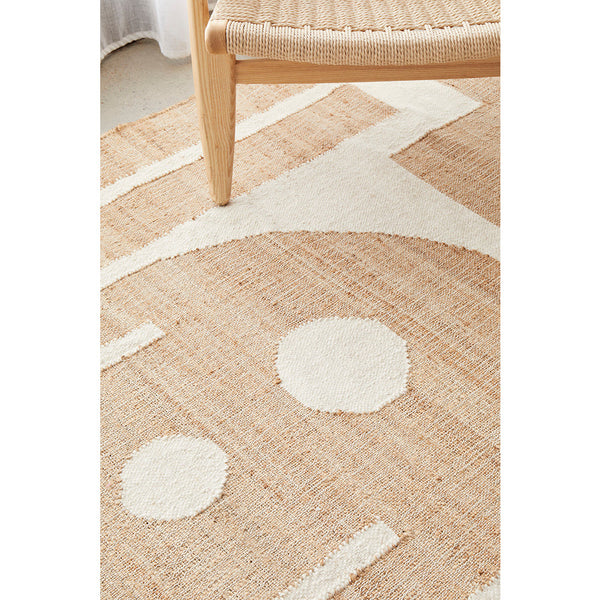 Neutral-toned flatwoven jute and cotton rug with geometric patterns under light wood chair legs.