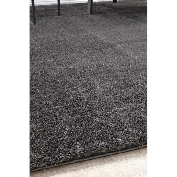 Soft shaggy grey polyester rug with dense pile on light wooden floor.