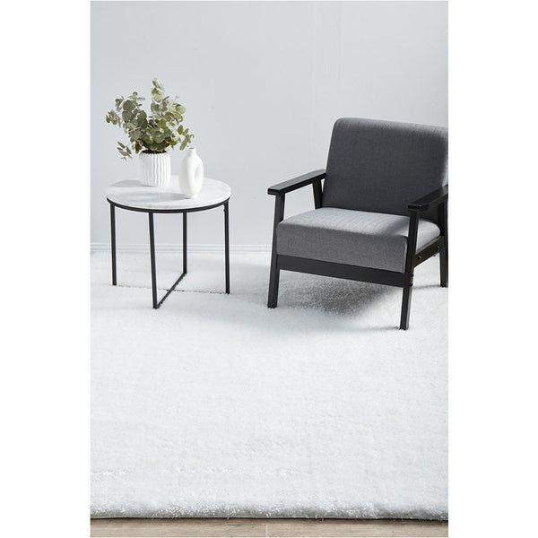Ivory soft shaggy rug with thick polyester pile under black armchair and white side table.
