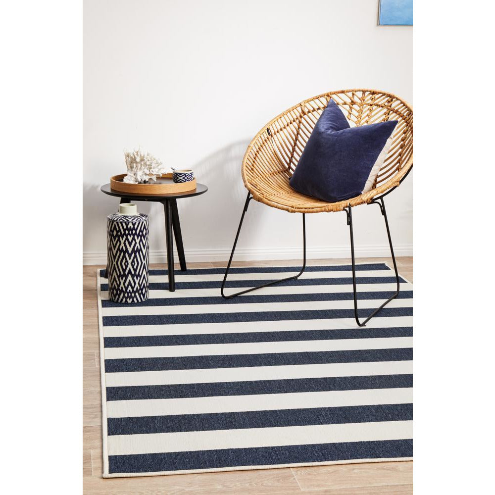 Coogee navy blue and white striped modern rug with beige border in a cozy indoor setting.