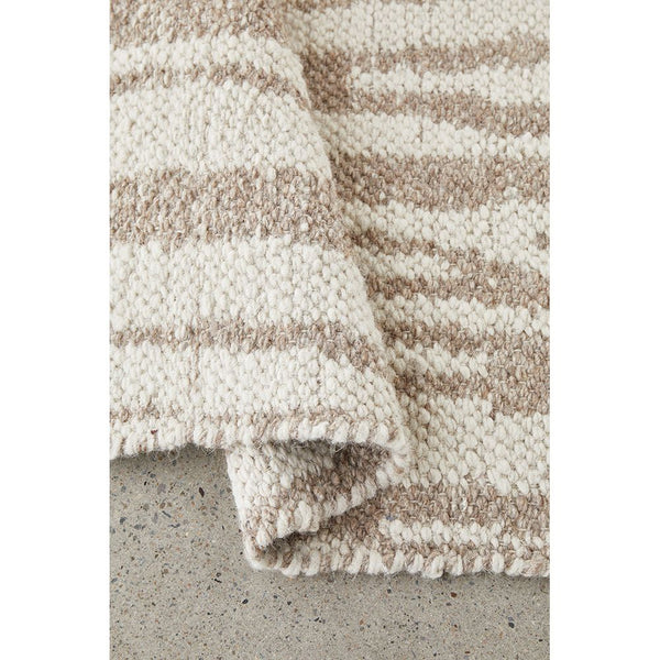 Neutral-toned wool blend rug with textured, handwoven flatweave pattern in beige and cream colors.